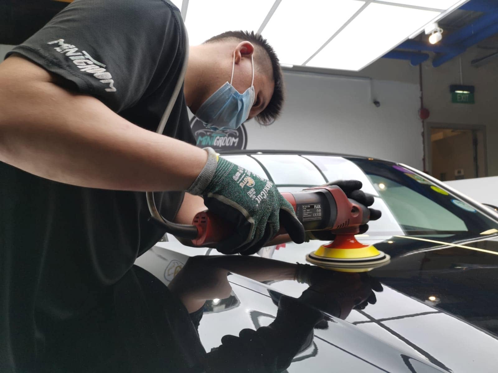 MintGroom detailer machine-polishing the paintwork of a black car